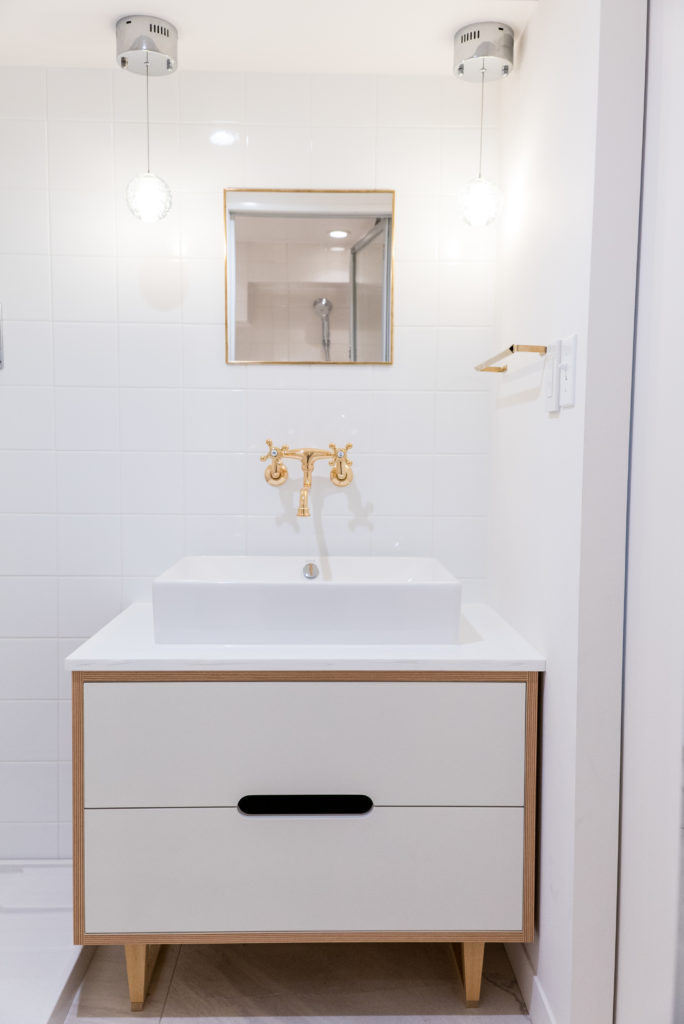 清潔感のある白が美しい洗面所。壁紙ではなくタイル。水栓の上品なゴールドが印象的。