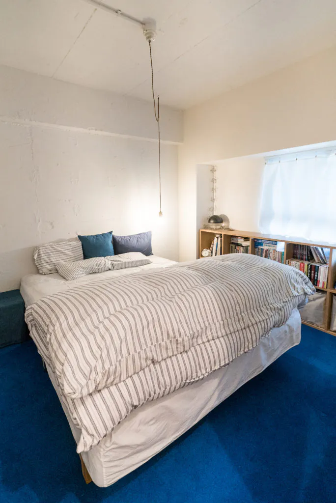 ブルーのカーペットとファブリックの白が映える寝室