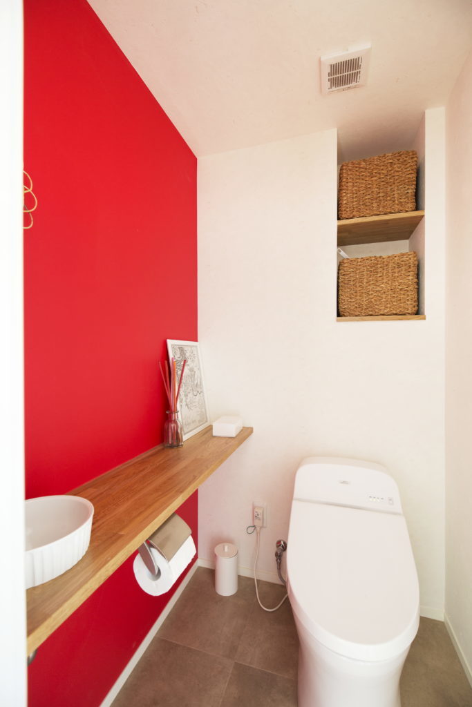 ビビットな赤の壁が雑貨屋さんのようでおしゃれなトイレ